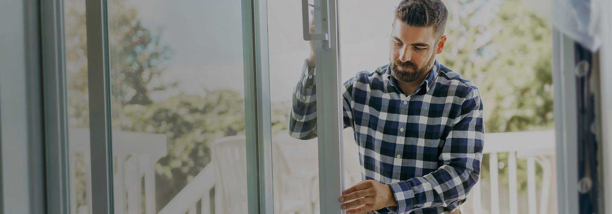 Mann steht hinter einem halb geoeffneten Fenster