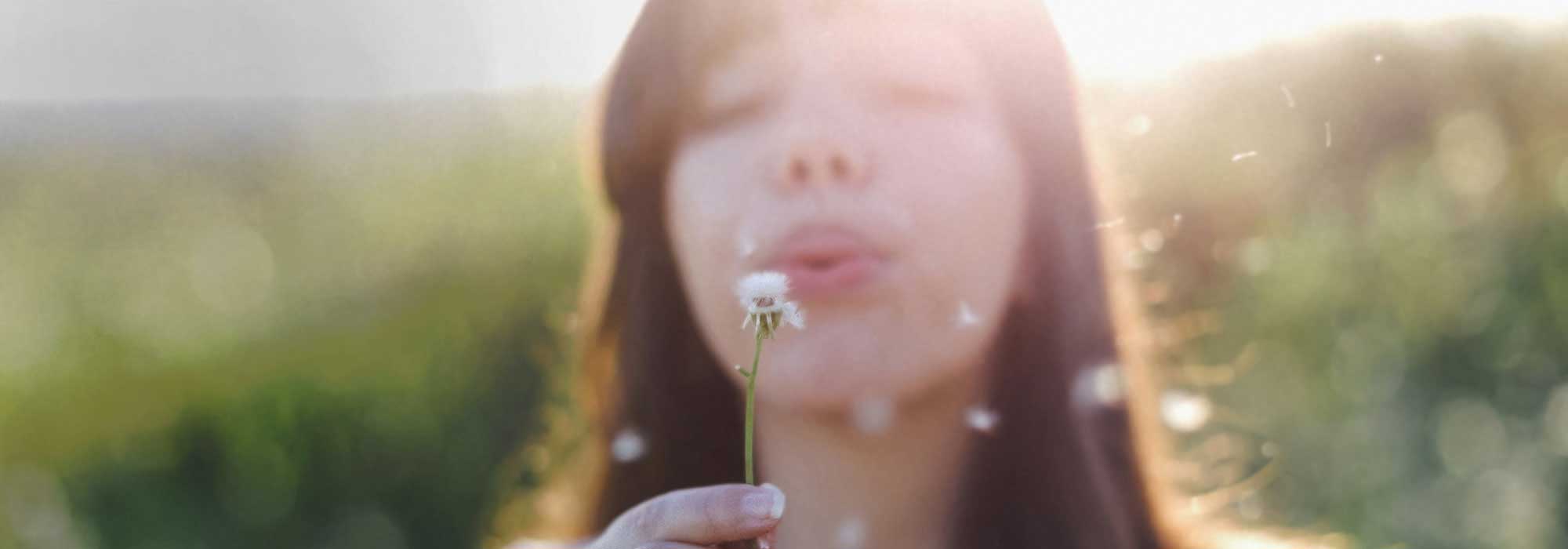 Frau mit Pusteblume in der Hand